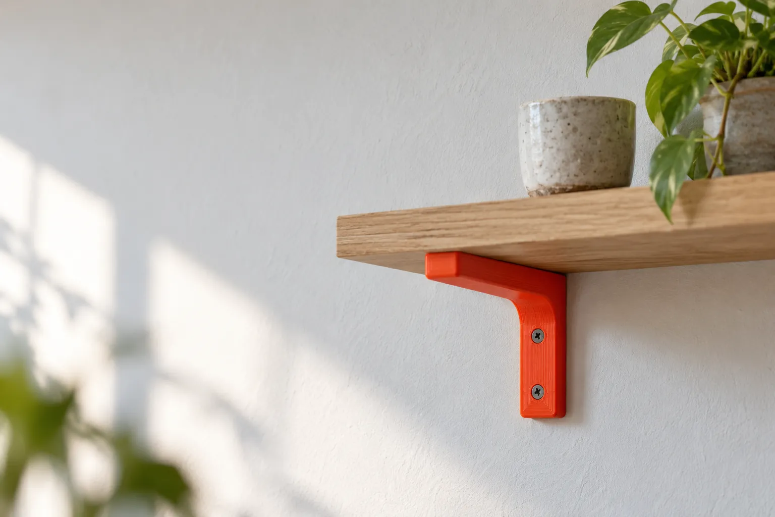 Illustration: an orange 3D printed bracket holding up a wooden shelf on a white wall.